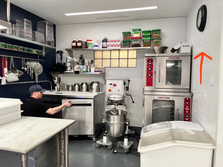 Eric Frankel’s photo of The Bear’s kitchen set, with a red arrow pointing to the wall beside the ovens where the sign hangs