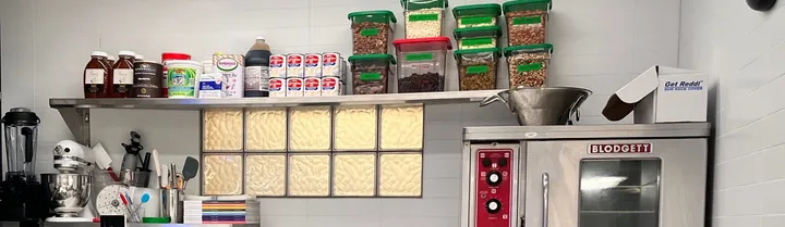 The set’s top shelf: molasses, cans and green-lidded storage containers above a convection oven