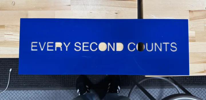 The first test: white letters showing through a cut-out bright blue acrylic panel on a workbench