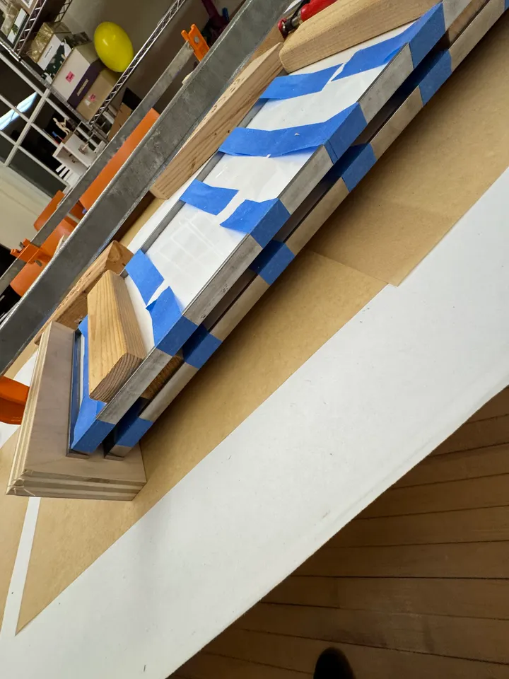 A sign frame held with blue tape and wood blocks, left to set overnight