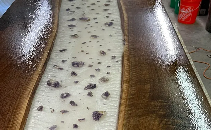 A wooden river table coated in glossy epoxy, the reference for the rippled finish
