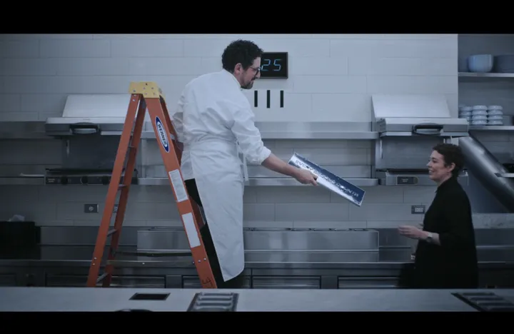 Season 3 still: a chef on a ladder hands the sign down to Chef Terry in the kitchen at Ever